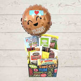 Gift box filled with treats and balloon that says 